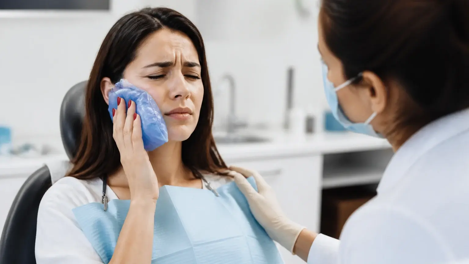 Urgent dental care desk with triage notes, ice pack, and patient holding jaw for emergency assessment
