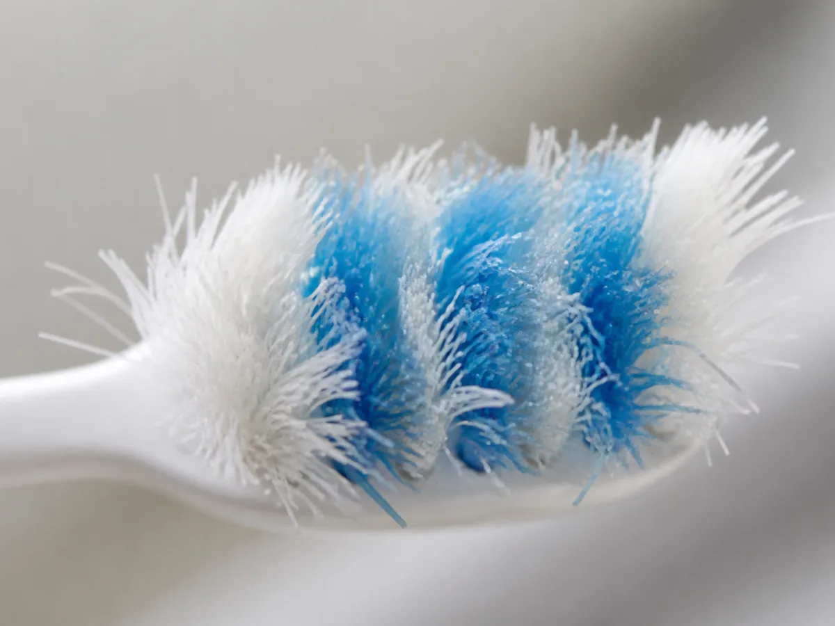 Fingertip demonstrating light toothbrush pressure against teeth in a mirror
