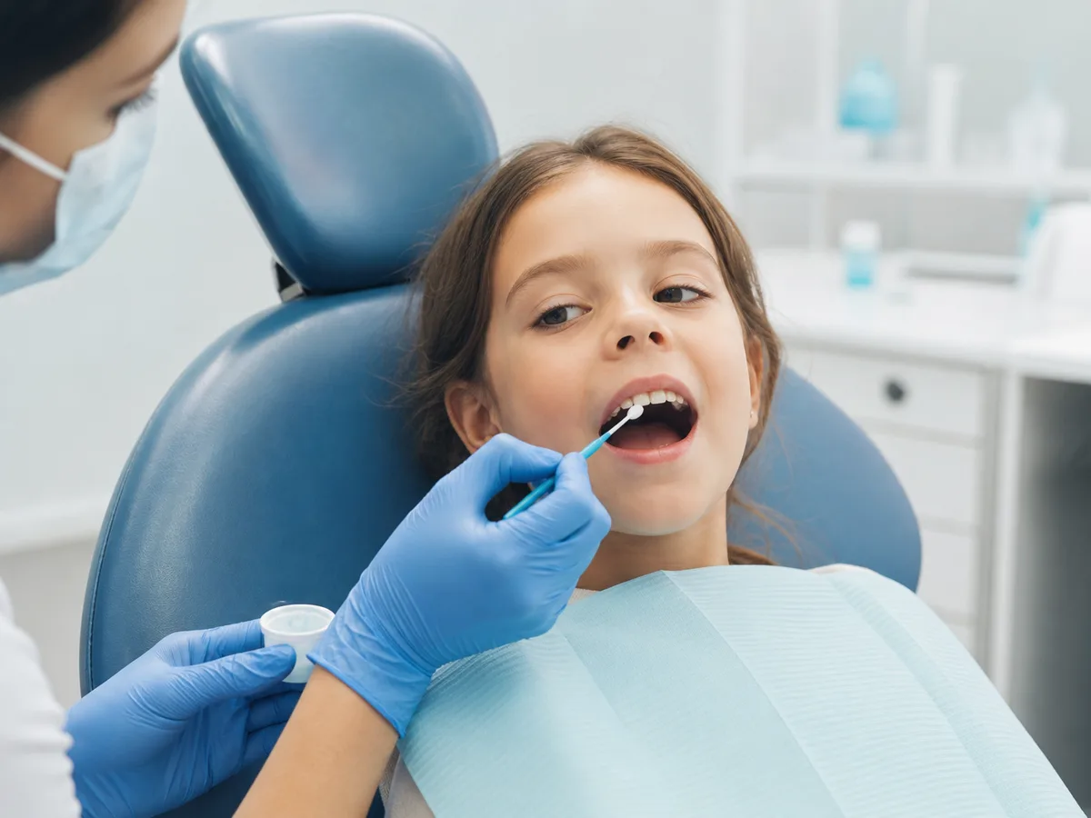 Pediatric dentist discussing fluoride varnish with a parent and child
