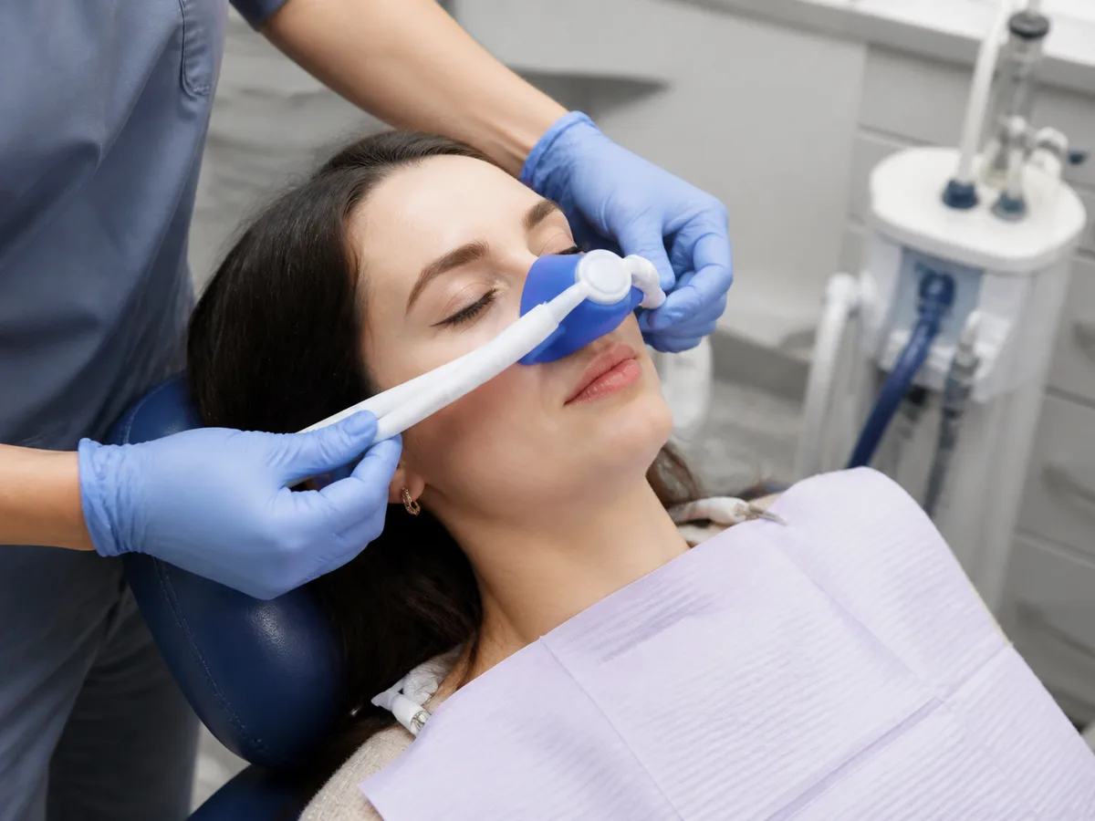 Dentist adjusting nitrous oxide and oxygen levels while checking in with a relaxed patient