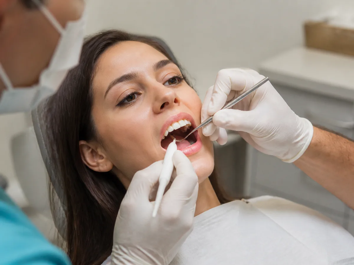 Dentist examining a broken tooth fragment next to a dental X-ray
