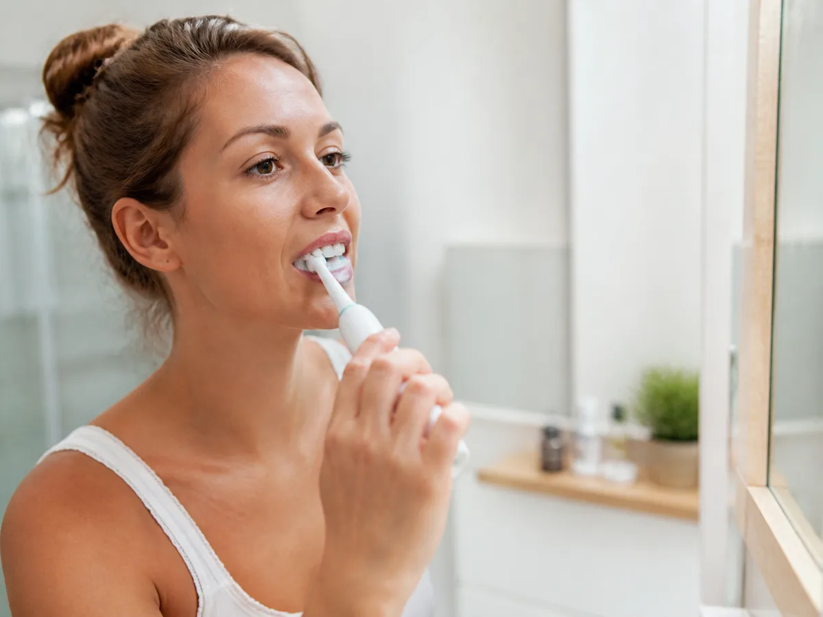 Person brushing along the gumline at home as part of daily plaque control