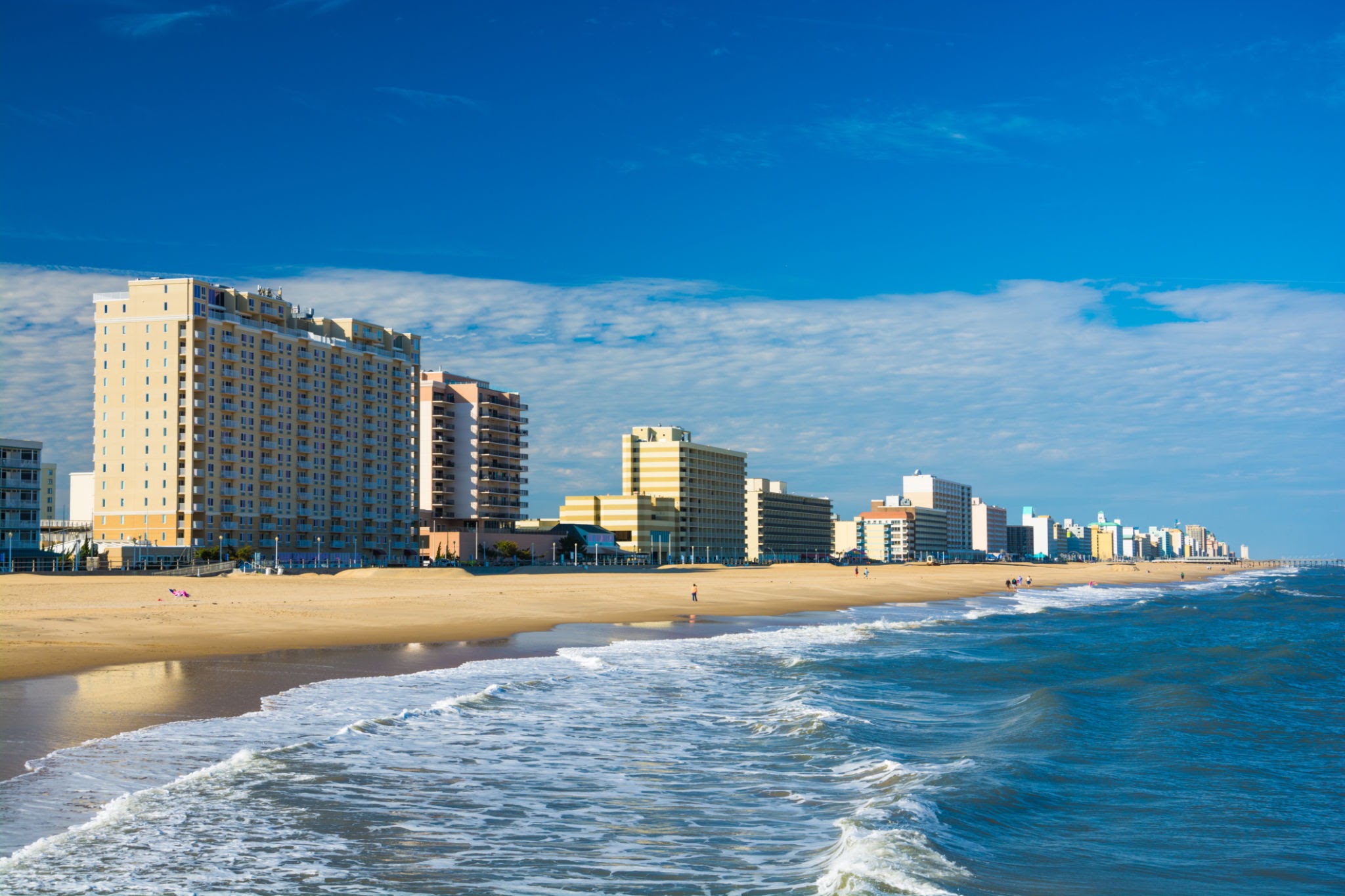 Virginia Beach’s coastal skyline with hotels and condominium towers, and with the Virginia Beach coastline and people in the foreground. Virginia Beach is part of the Hampton Roads area.