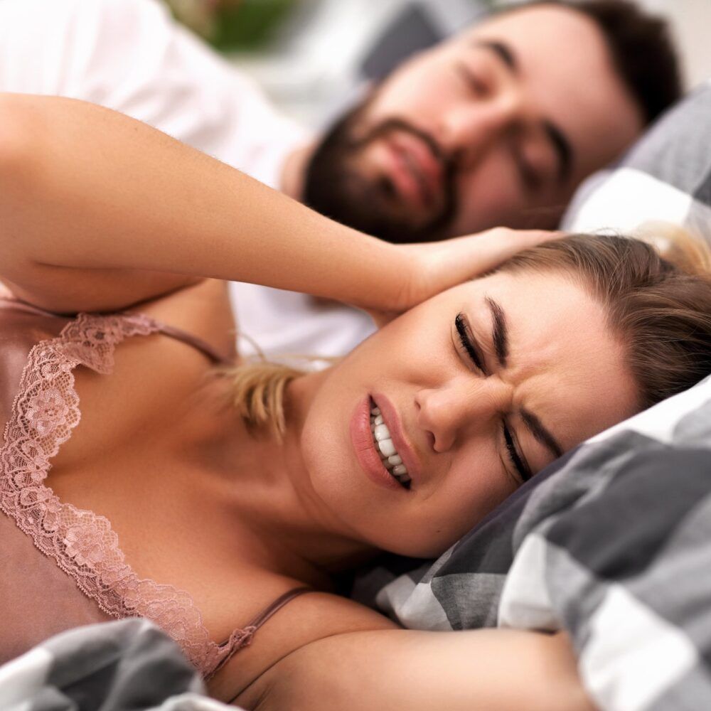 Adult couple suffering from snoring problem in bed