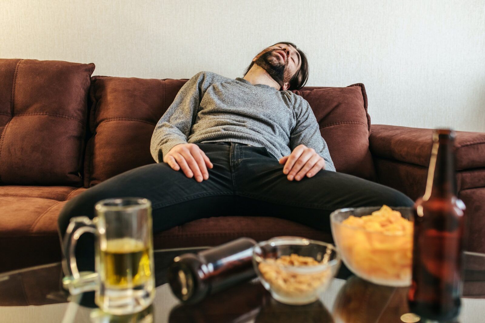 Drunk young man sleeping on sofa after party at home.