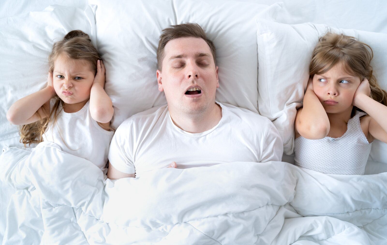 Kids, dad sleep together in bed. Father snoring hard, girls, daughters are plugging ears with pillow
