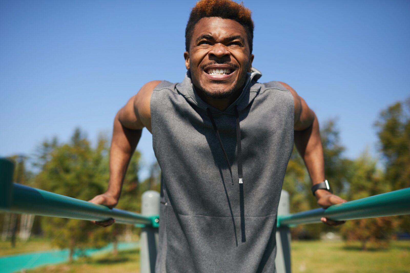 Black man with clenched teeth doing dips