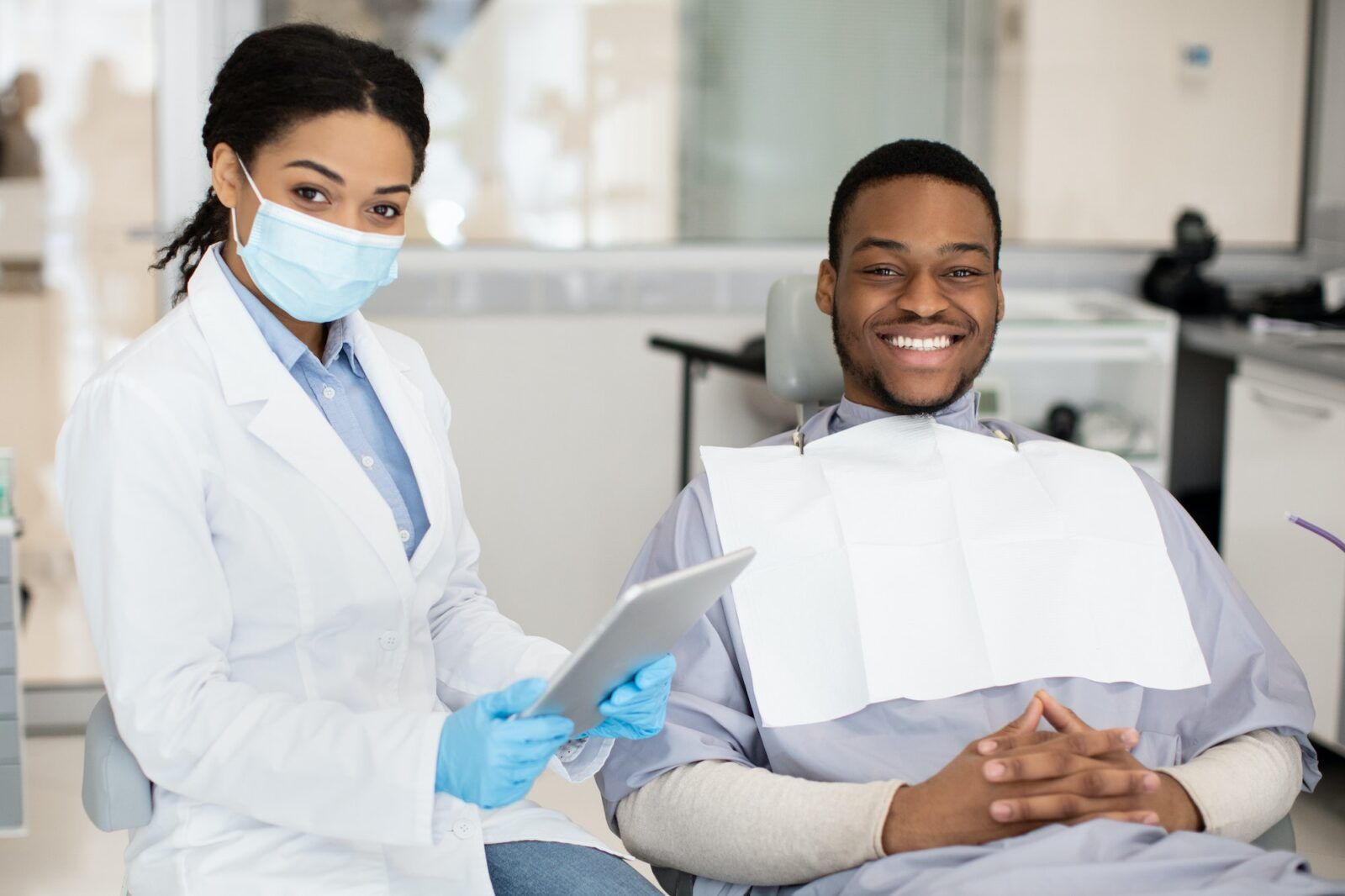 Dental Insurance Concept. Black Dentist Woman And Male Patient Posing In Clinic