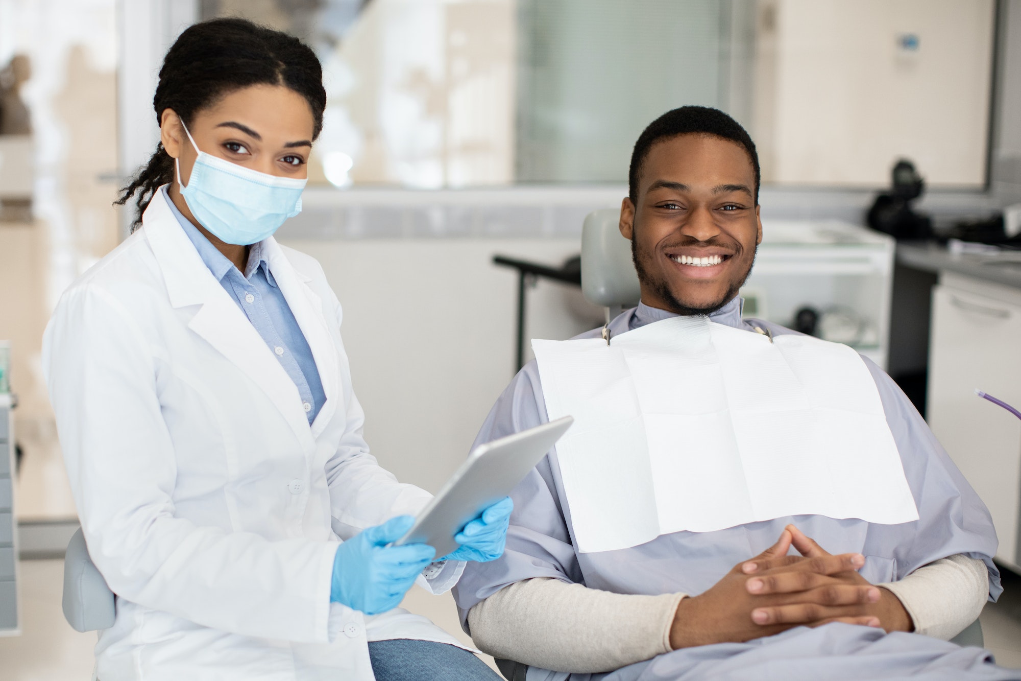 Dental Insurance Concept. Black Dentist Woman And Male Patient Posing In Clinic