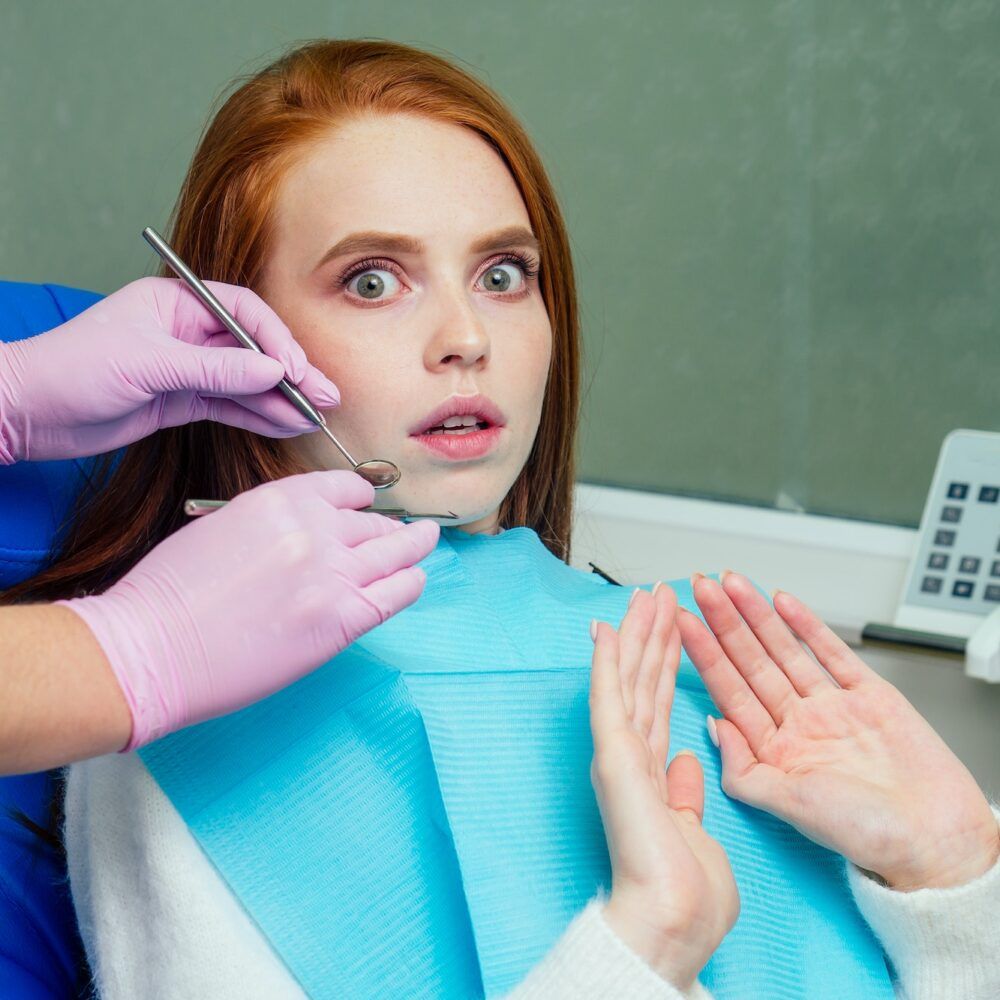 redhaired ginger stressed female patient afraid on checkup dental examination in clinic