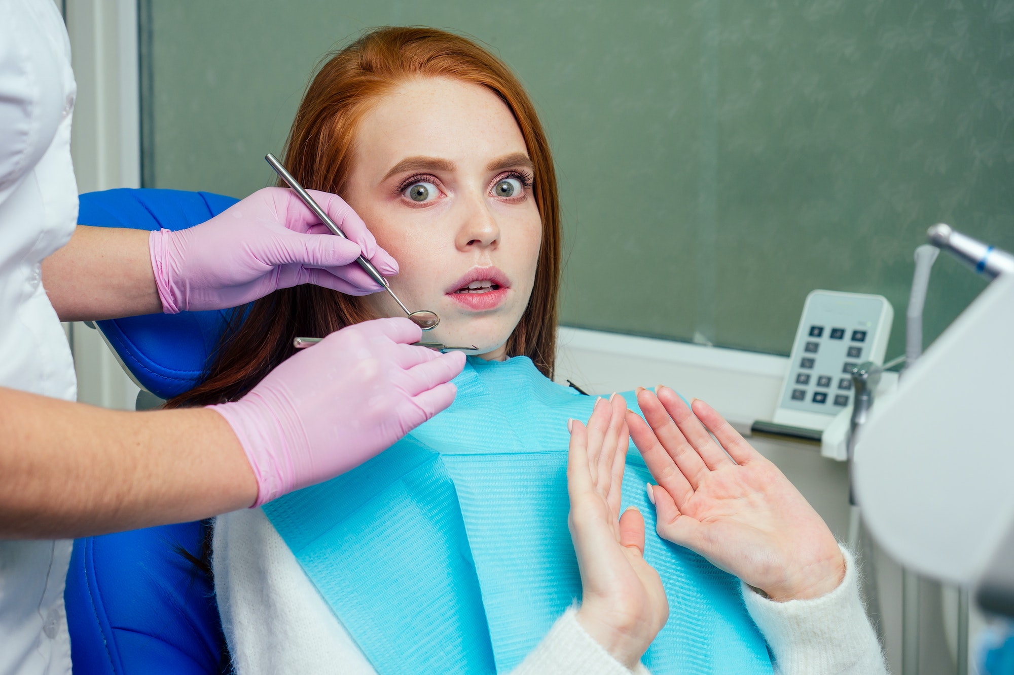 redhaired ginger stressed female patient afraid on checkup dental examination in clinic