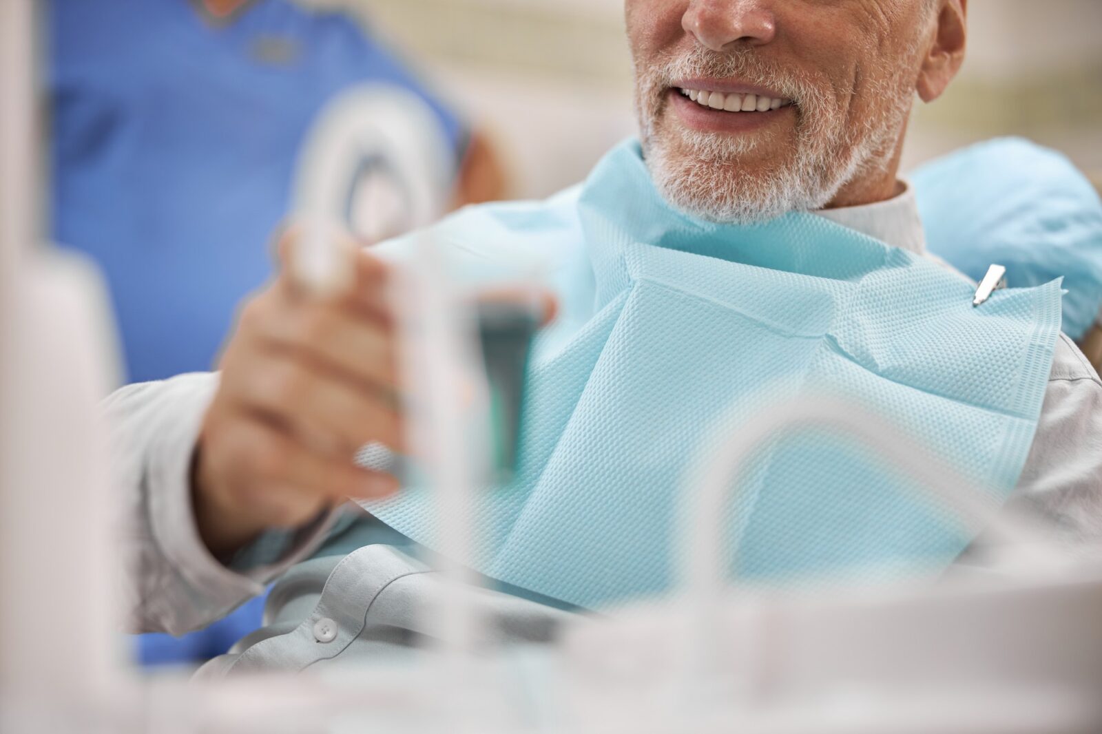 Senior patient having a cup with a mouthwash to rinse his mouth