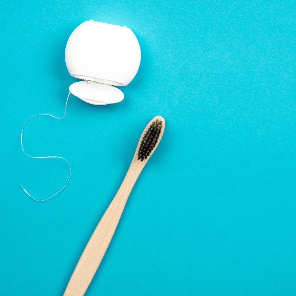 Toothbrush and dental floss on blue background