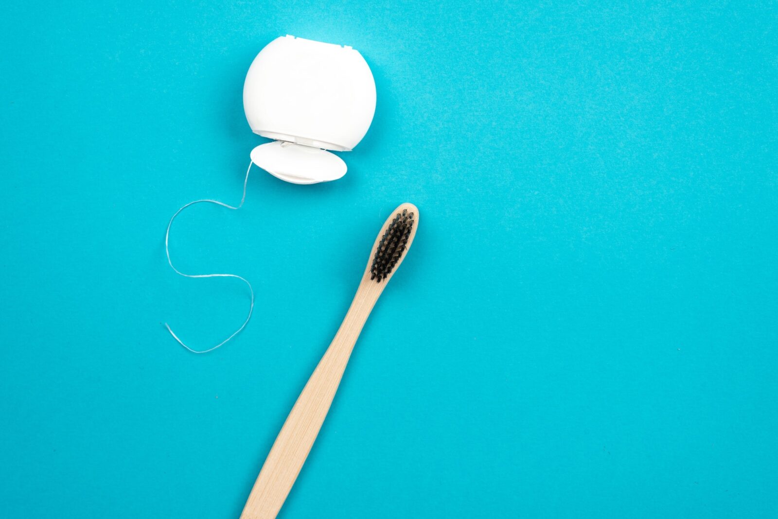 Toothbrush and dental floss on blue background