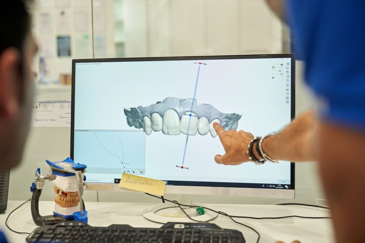 Unrecognizable prosthodontists examining denture on computer