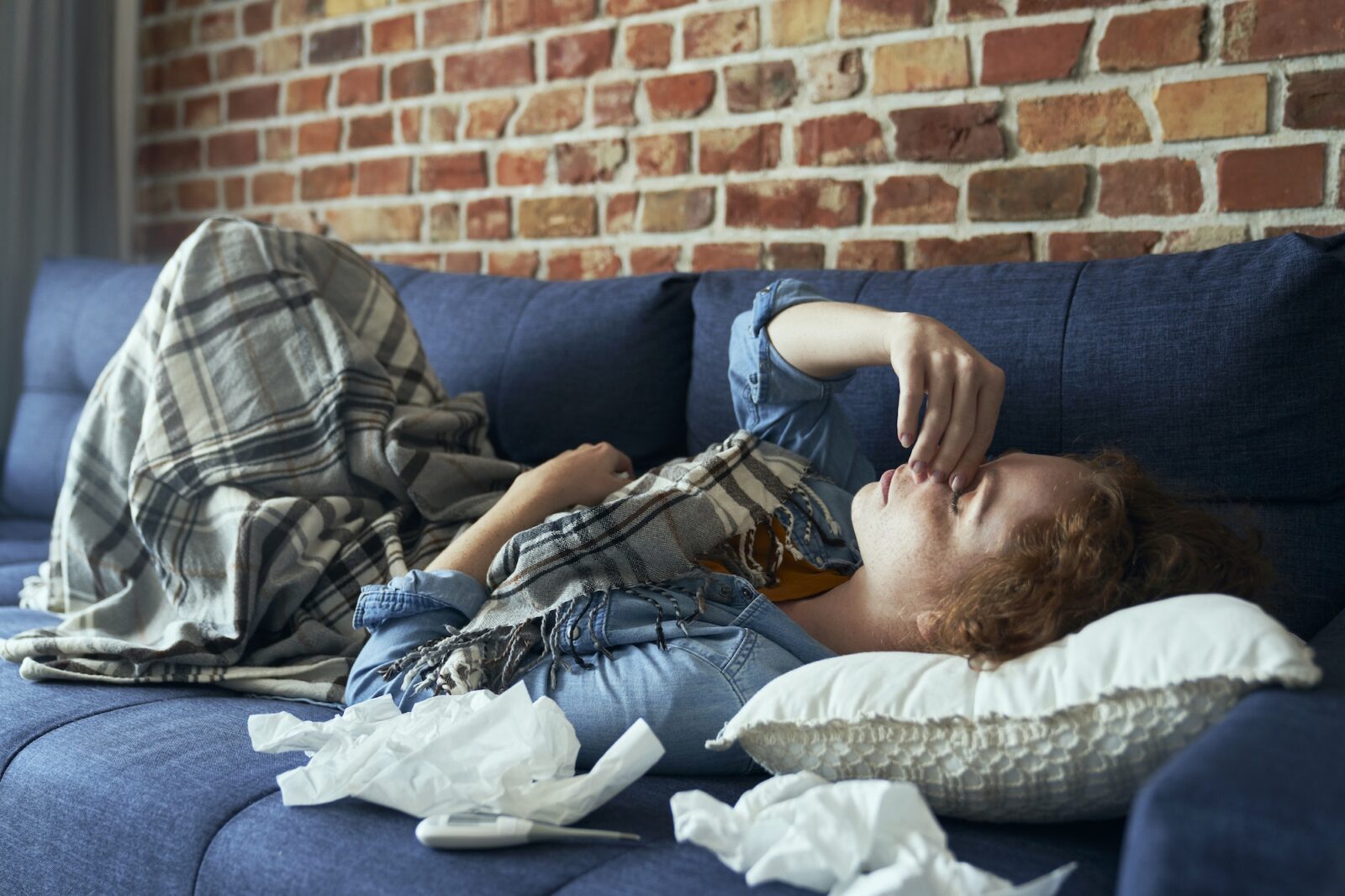 Young caucasian woman lying on sofa and having a serious sinus infection