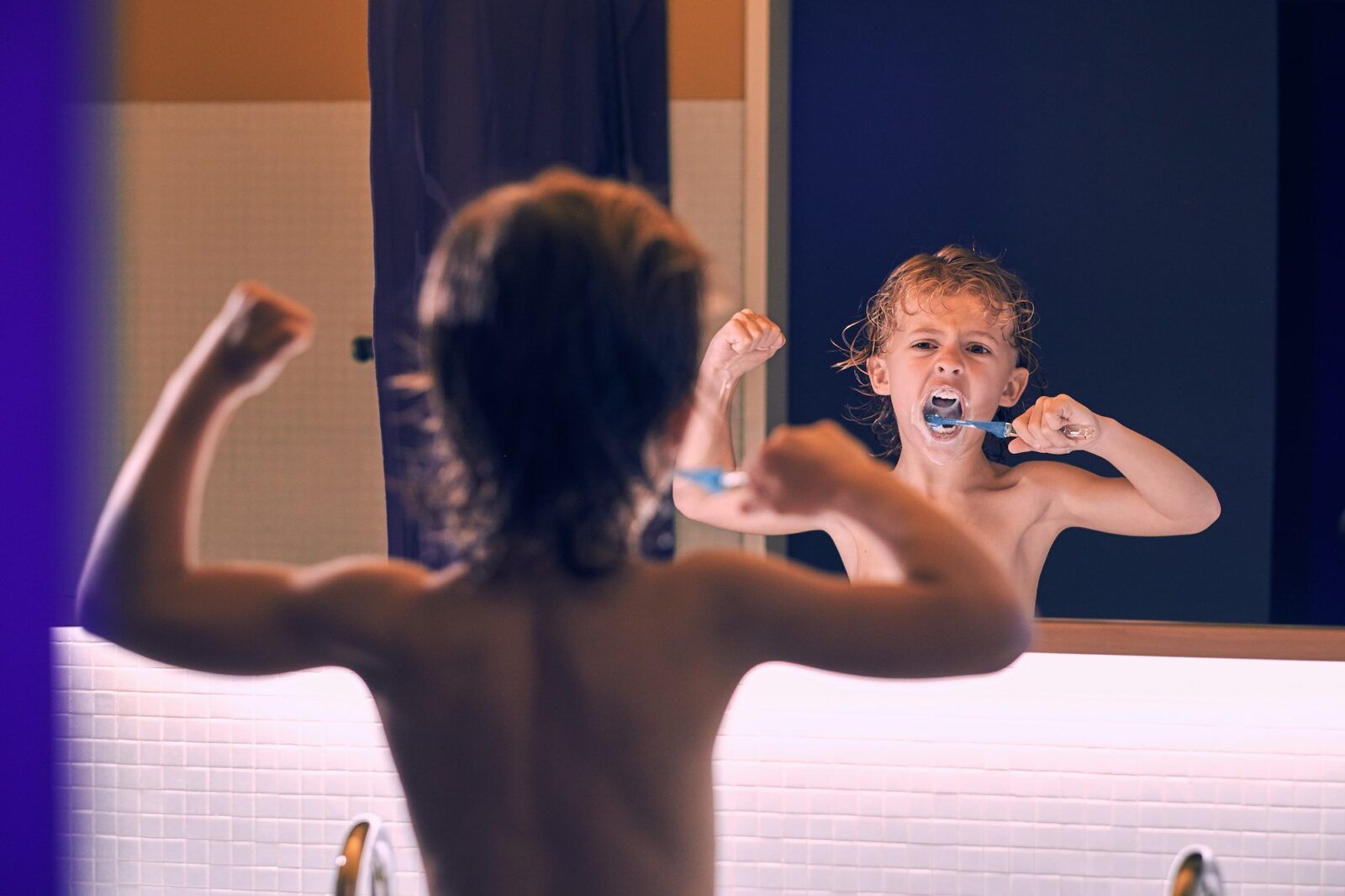 Angry boy raising fist while brushing teeth