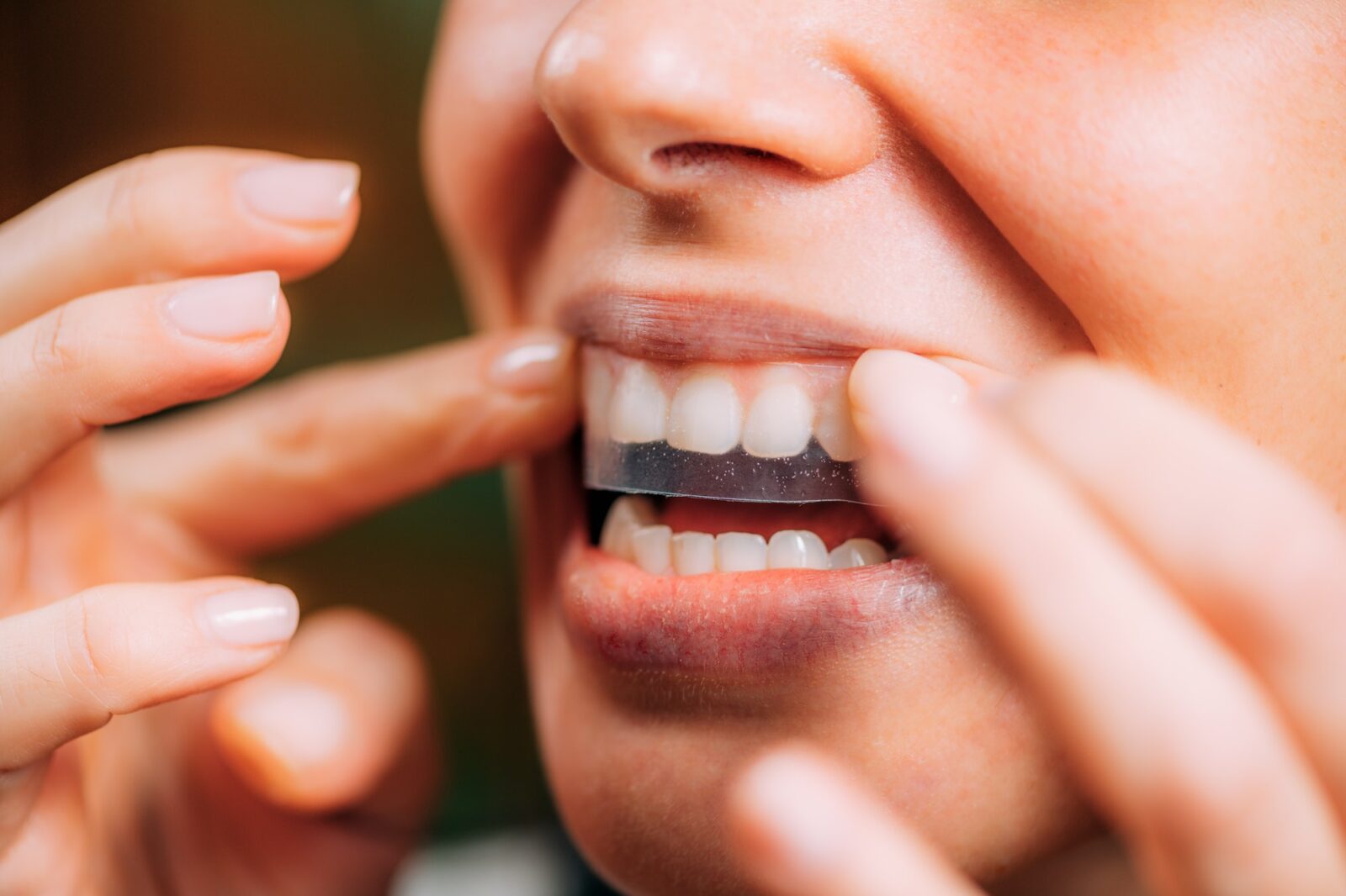 Woman using whitening stipes or whitestrips. Whitening teeth at home.