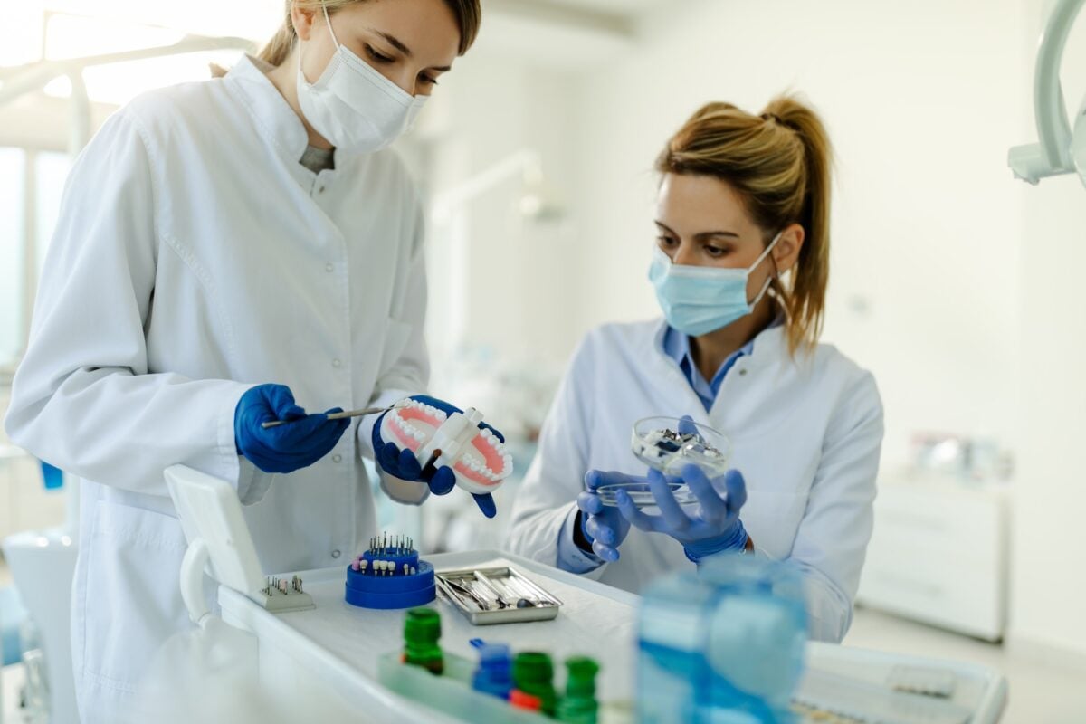 Dental technician dentist woman working with dentures in a laboratory with wax on a jaw model.