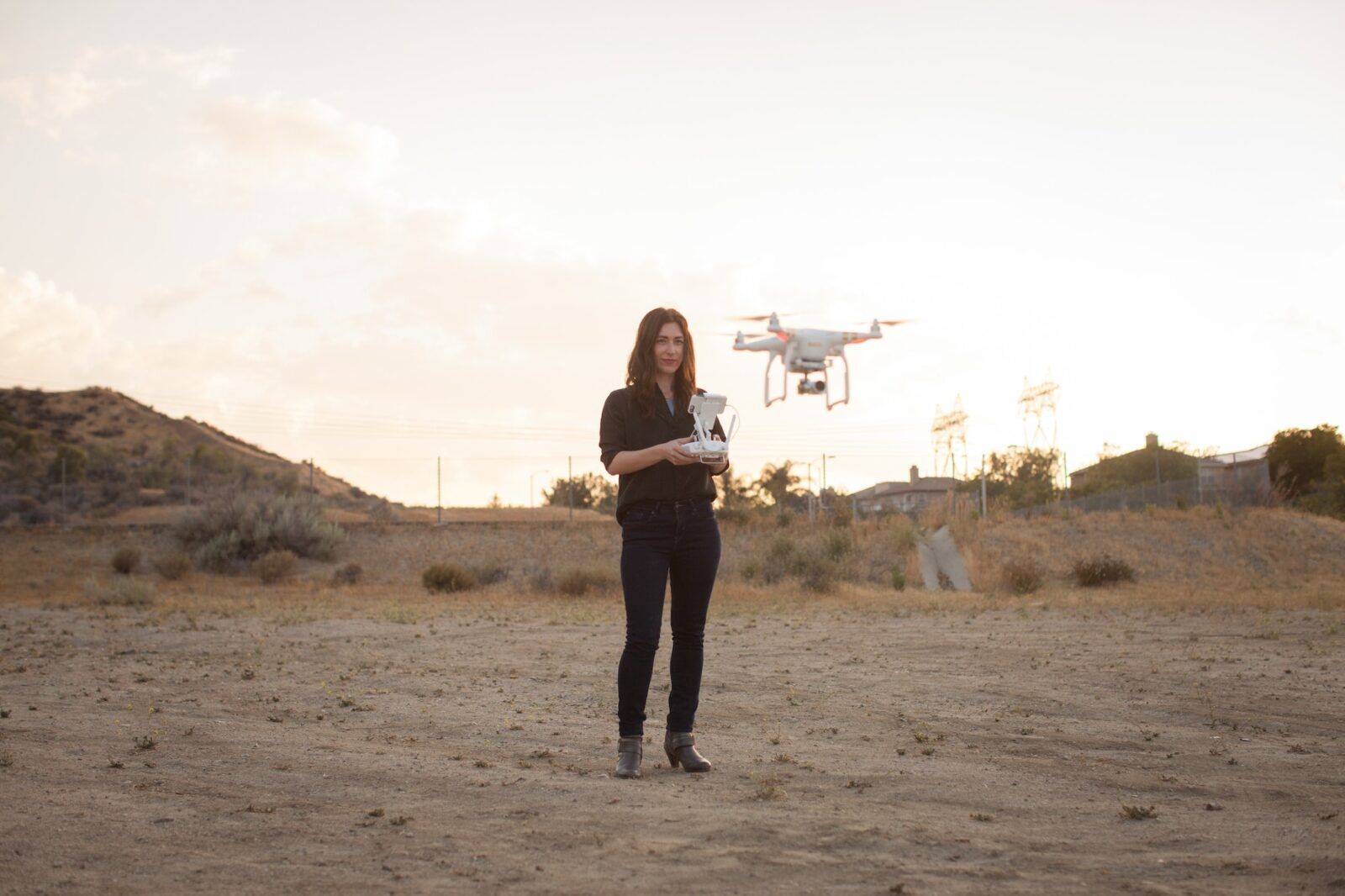 Female commercial operator on scrubland flying drone, Santa Clarita, California, USA
