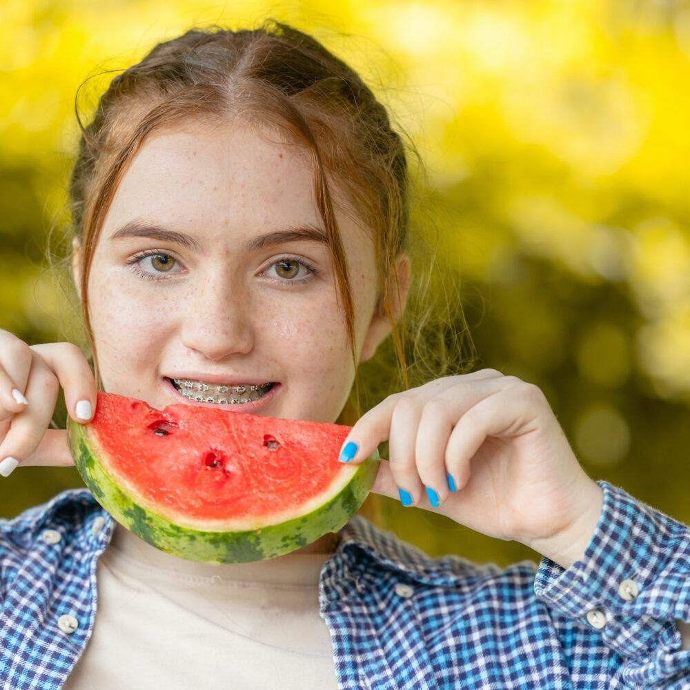 beautiful teen girl smiling with watermelon and dental care orthodontic treatment teeth aligning w