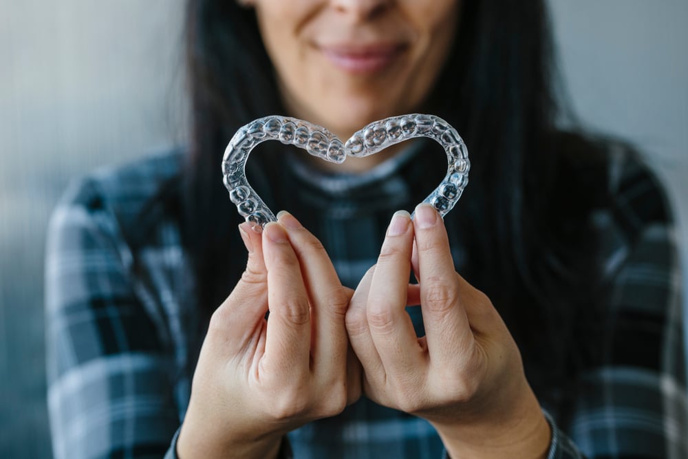 Patient Making A Heart Shape With Dental Aligners