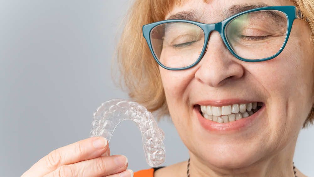 older woman holding clear aligners