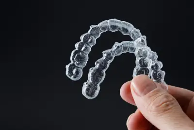 Hand holding two transparent retainers on black background. Invisalign orthodontics concept