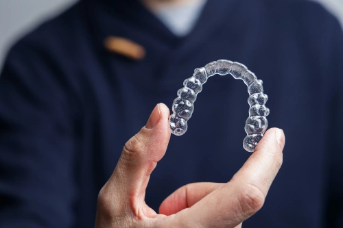 Man holding one transparent aligner. Invisalign orthodontics concept